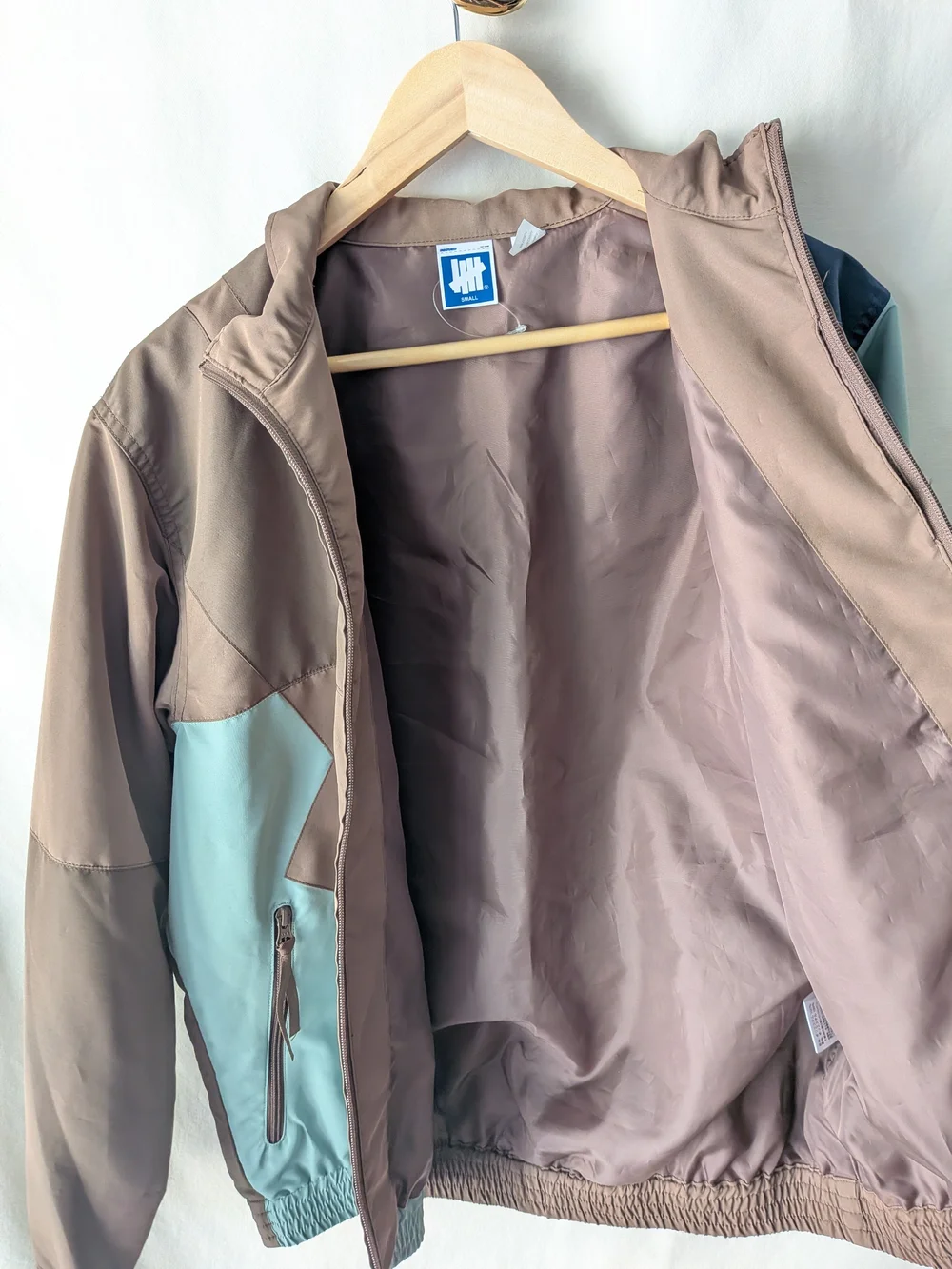 Undefeated Jacket in Taupe and Beige with Blue Logo Tag